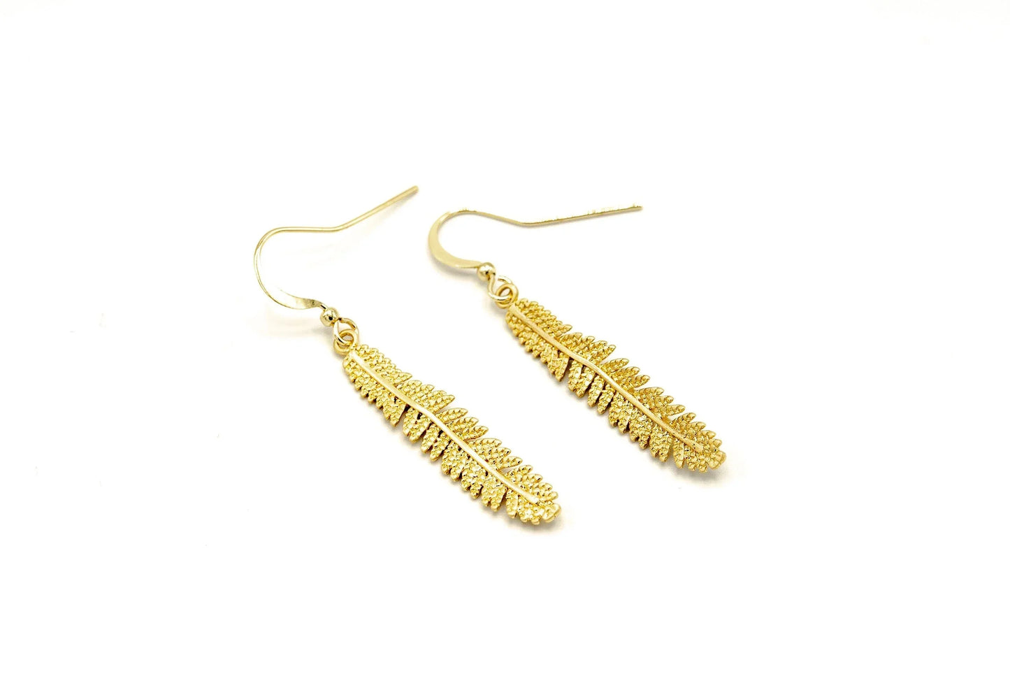 gold dangle earrings with long textured leaf design on white background