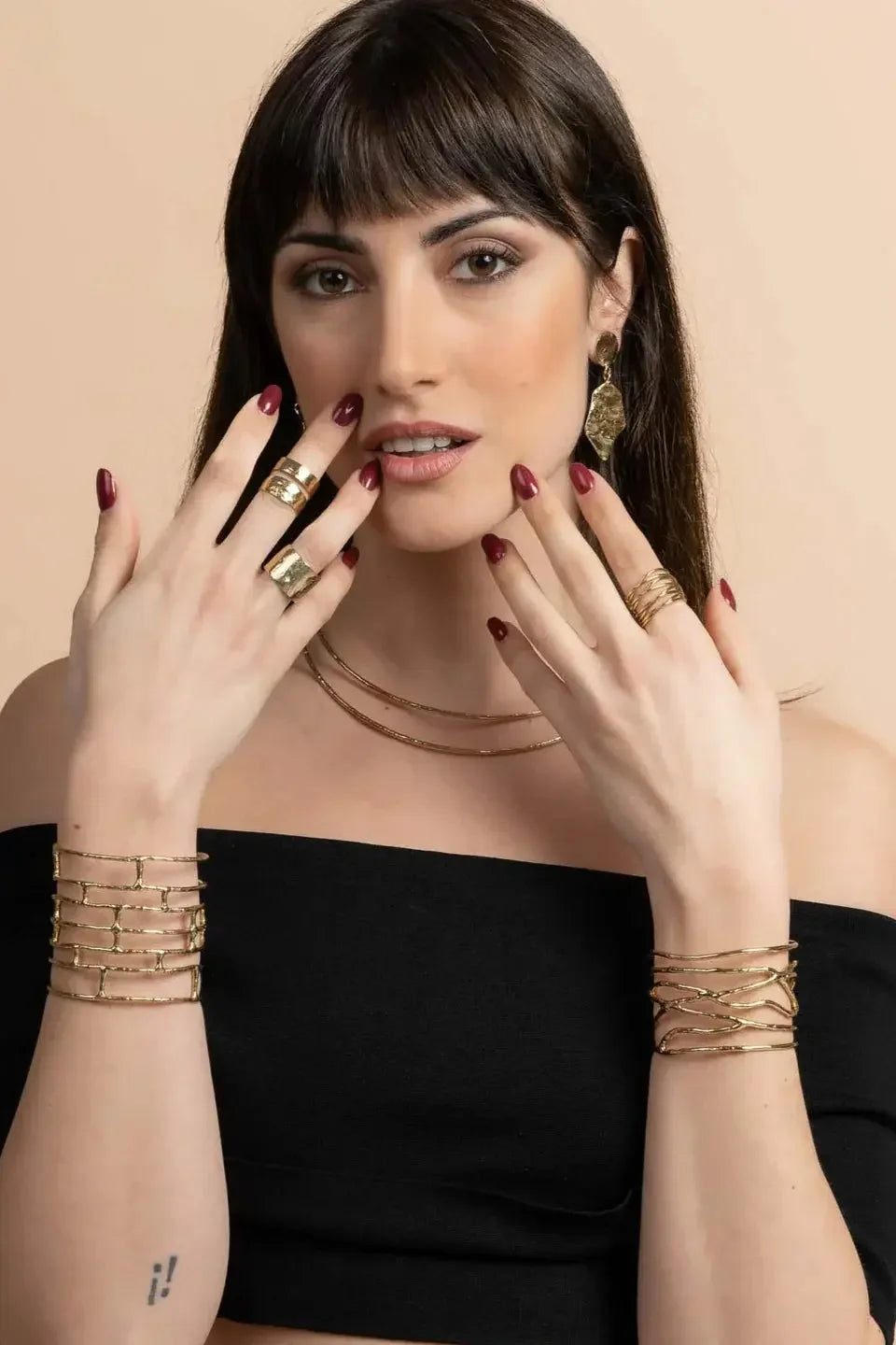Woman wearing gold statement jewelry set, including bracelets, rings, earrings, and necklaces