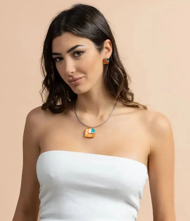 Woman wearing geometric gold and turquoise necklace and matching earrings on neutral background