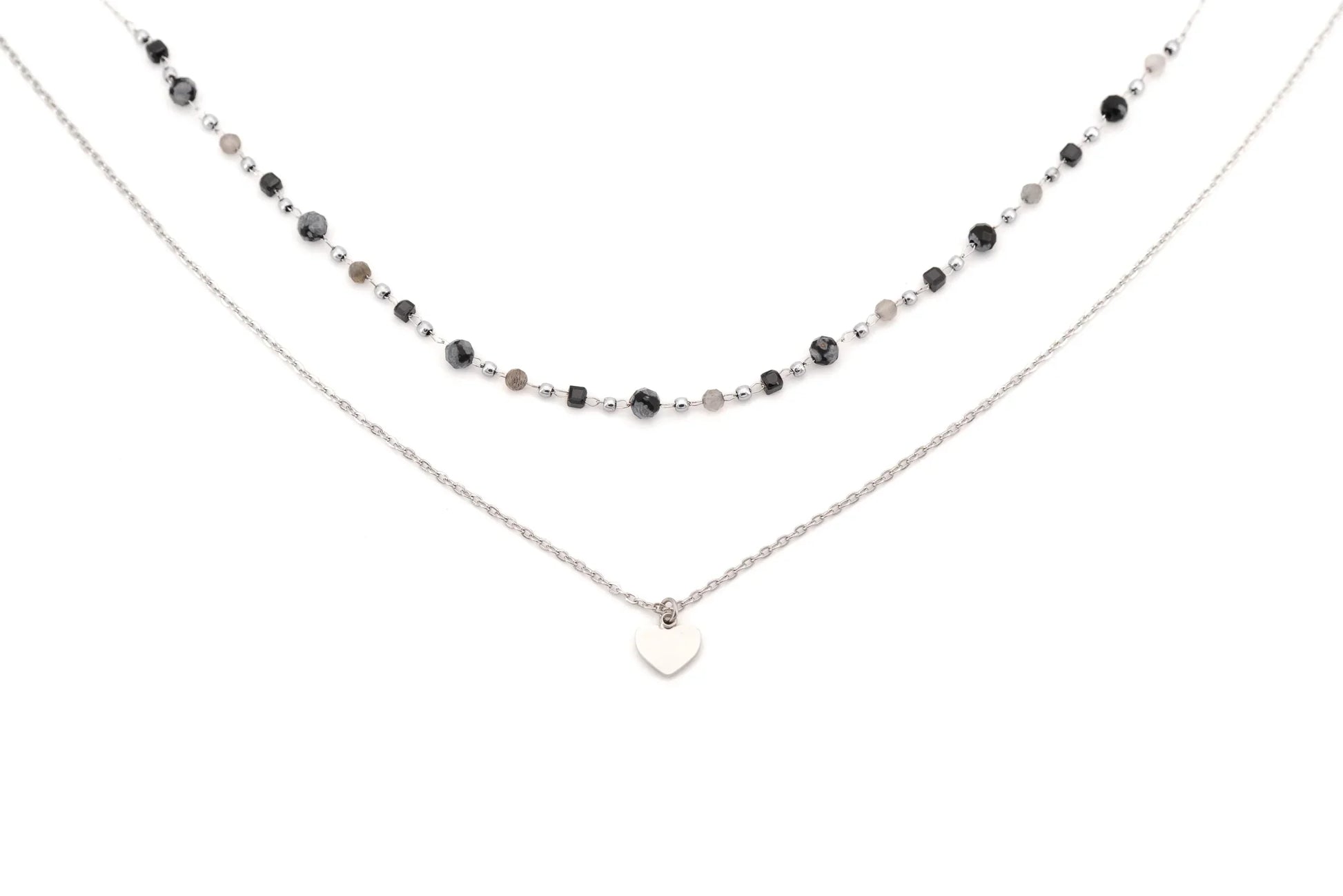 Layered necklace with black and silver beads and a silver heart pendant on white background